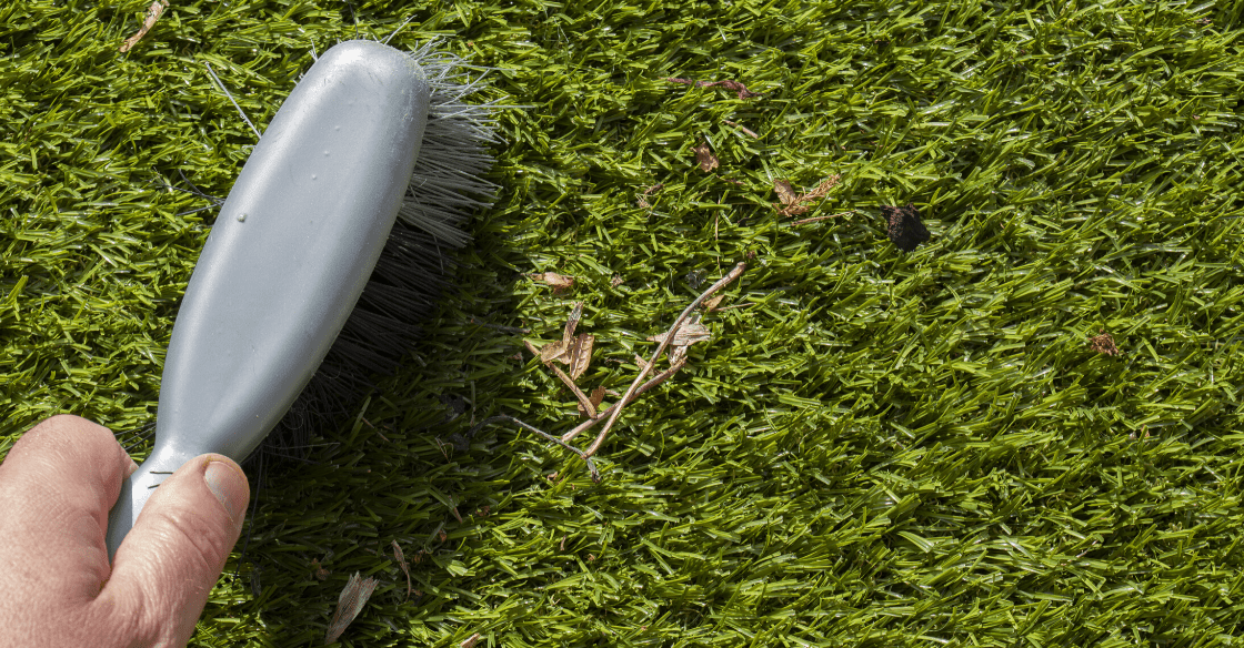 Cleaning artificial turf with brush