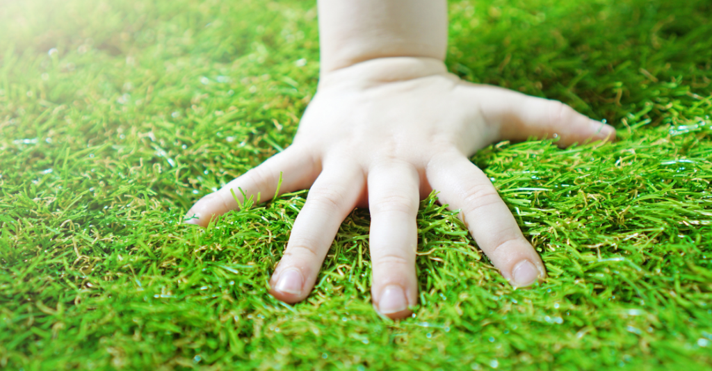 person pressing their hand on their artificial lawn